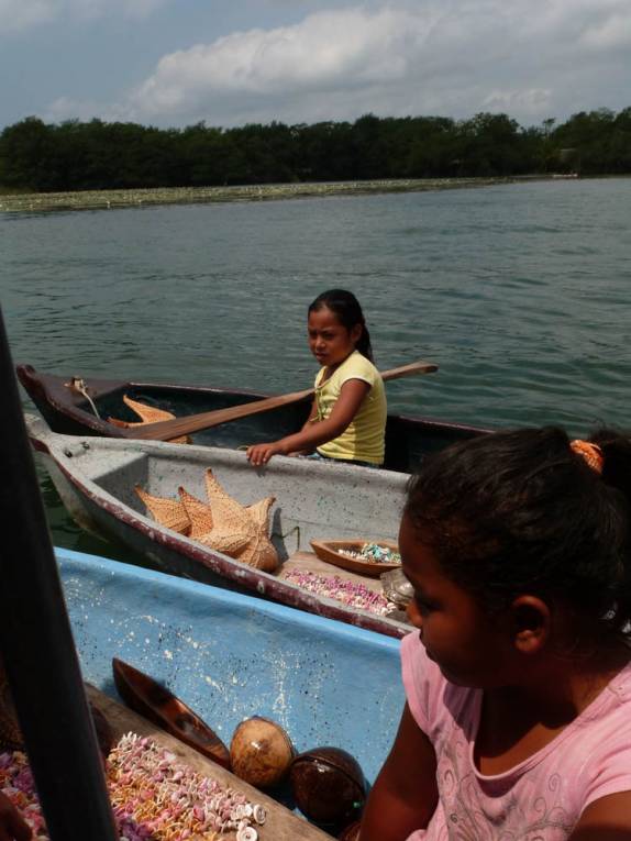Meninas vêm em suas canoas nos vender artesanato, no caminho para Livingston, no litoral da Guatemala